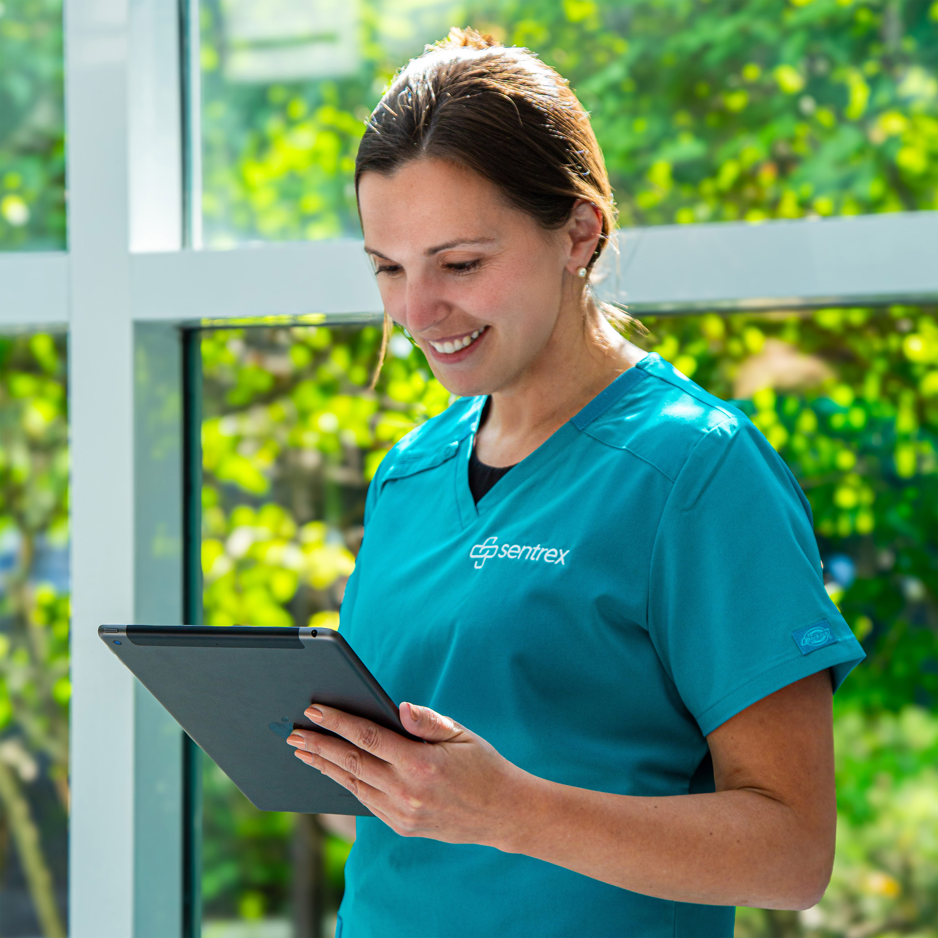Healthcare professional looking at a tablet near a window